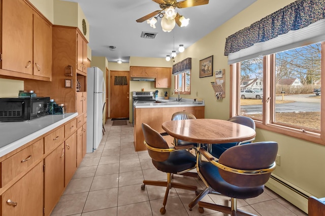 kitchen with light tile patterned floors, visible vents, freestanding refrigerator, under cabinet range hood, and a sink