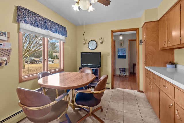 dining room with a baseboard heating unit, ceiling fan, and light tile patterned flooring