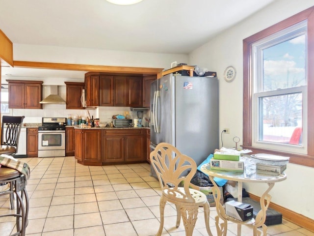 kitchen with stainless steel appliances, stone counters, wall chimney exhaust hood, and light tile patterned floors