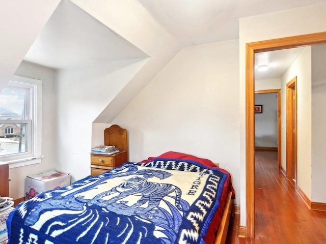 bedroom with baseboards, vaulted ceiling, and wood finished floors