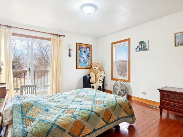 bedroom with baseboards, access to outside, visible vents, and wood finished floors