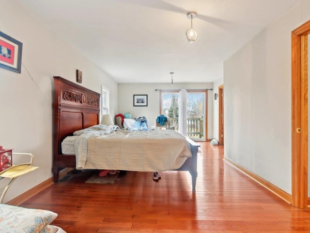 bedroom with baseboards, wood finished floors, and access to exterior