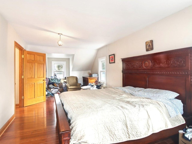 bedroom with dark wood-style floors, lofted ceiling, and baseboards