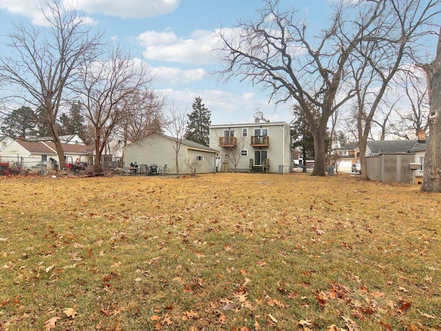 back of property with a balcony, fence, and a yard