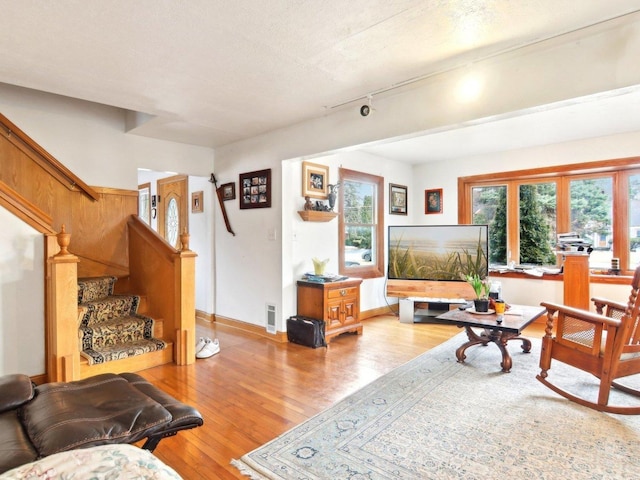 living room featuring stairway, rail lighting, light wood-style flooring, and baseboards