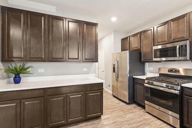 kitchen with appliances with stainless steel finishes, light countertops, dark brown cabinets, and light wood finished floors