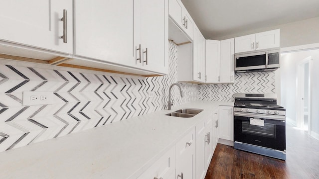 kitchen featuring stainless steel appliances, tasteful backsplash, light countertops, white cabinets, and a sink