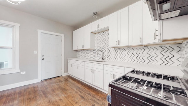 kitchen featuring light countertops, decorative backsplash, white cabinetry, and range with gas stovetop