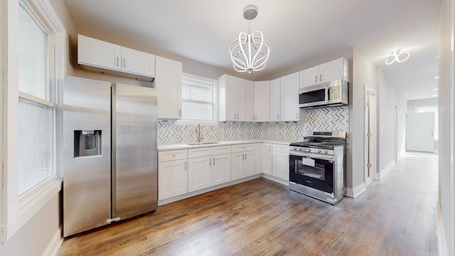 kitchen with light countertops, appliances with stainless steel finishes, white cabinetry, and decorative light fixtures