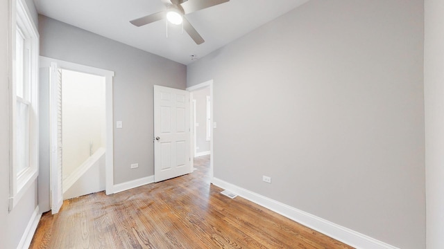 unfurnished bedroom featuring a ceiling fan, visible vents, light wood-style flooring, and baseboards