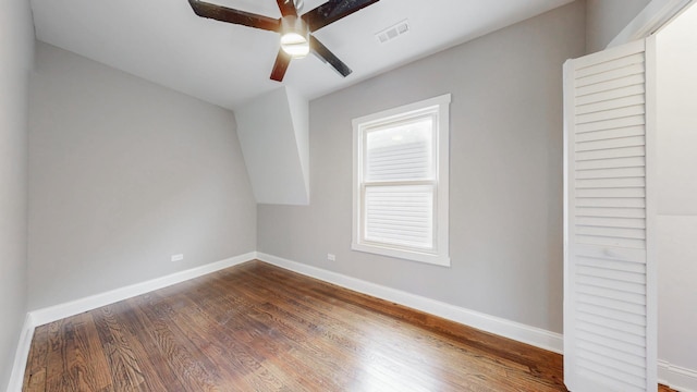 interior space featuring a ceiling fan, dark wood finished floors, visible vents, and baseboards