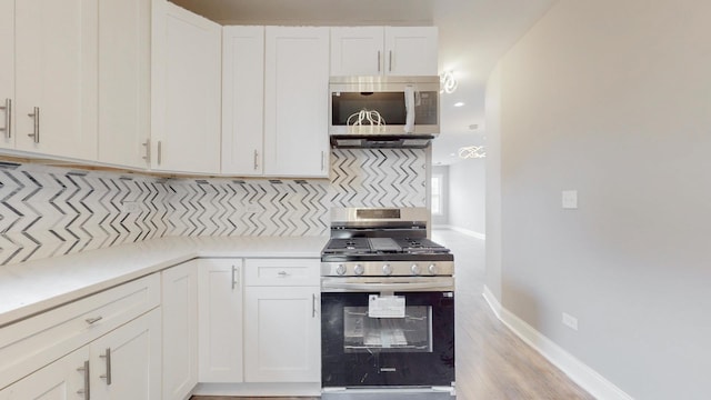 kitchen featuring tasteful backsplash, baseboards, stainless steel appliances, light countertops, and white cabinetry