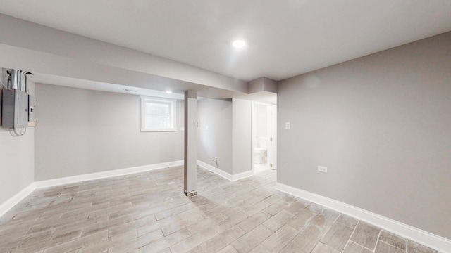 below grade area with light wood-style floors, recessed lighting, electric panel, and baseboards