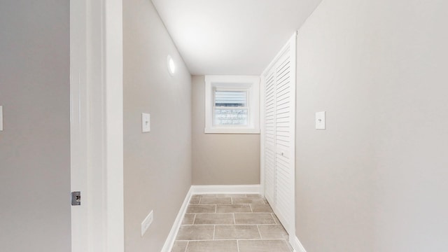 hall featuring light tile patterned flooring and baseboards