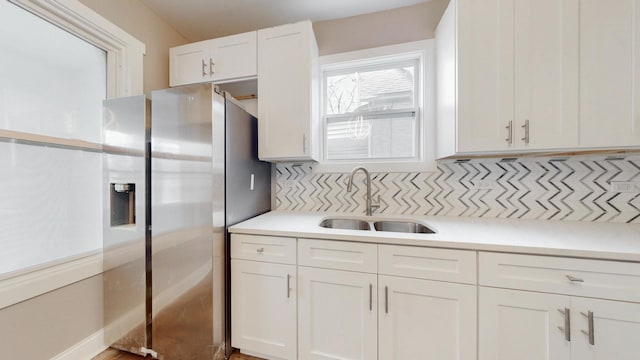 kitchen featuring light countertops, white cabinets, a sink, and stainless steel fridge