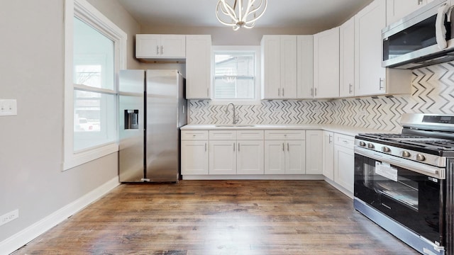 kitchen featuring appliances with stainless steel finishes, light countertops, a sink, and white cabinetry