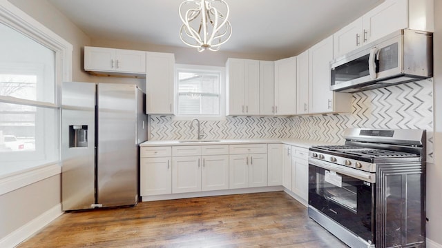 kitchen featuring appliances with stainless steel finishes, white cabinets, light countertops, and hanging light fixtures