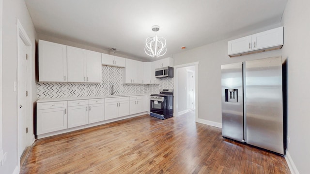 kitchen featuring pendant lighting, light countertops, decorative backsplash, appliances with stainless steel finishes, and white cabinets