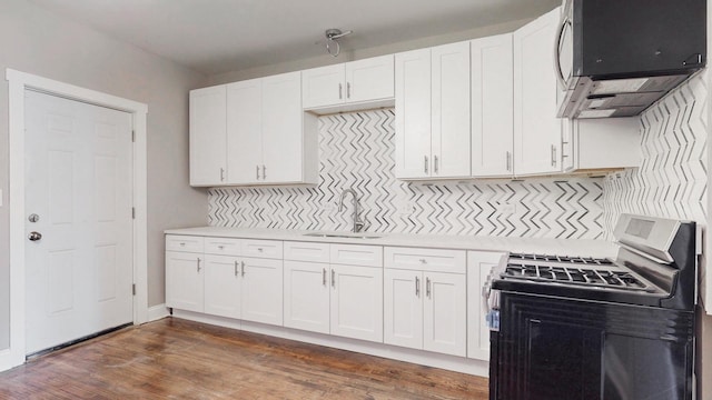 kitchen with tasteful backsplash, light countertops, white cabinetry, a sink, and gas stove