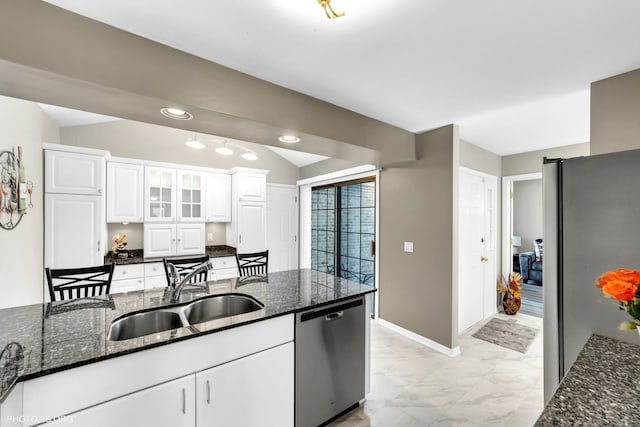 kitchen featuring dark stone counters, marble finish floor, stainless steel appliances, white cabinetry, and a sink