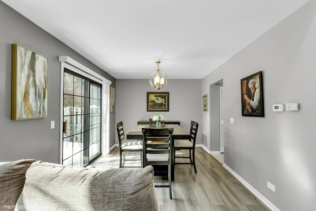 dining room with light wood-style floors, visible vents, baseboards, and an inviting chandelier