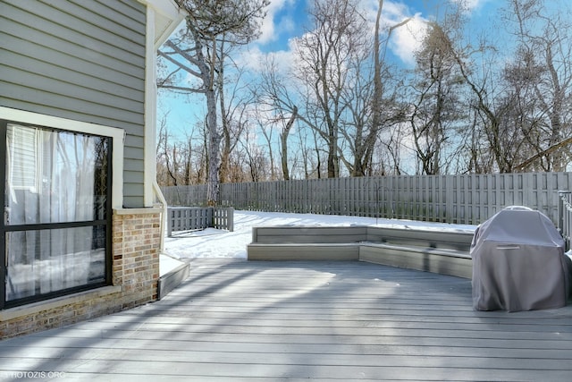 snow covered deck featuring a grill and fence