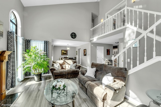 living area featuring stairway, wood finished floors, a towering ceiling, and a healthy amount of sunlight