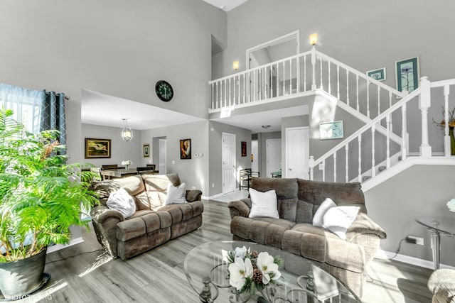 living room with a high ceiling, stairs, baseboards, and wood finished floors