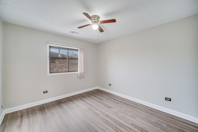 empty room with baseboards, a textured ceiling, visible vents, and wood finished floors