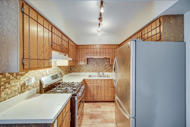 kitchen with stainless steel appliances, brown cabinetry, light countertops, and under cabinet range hood