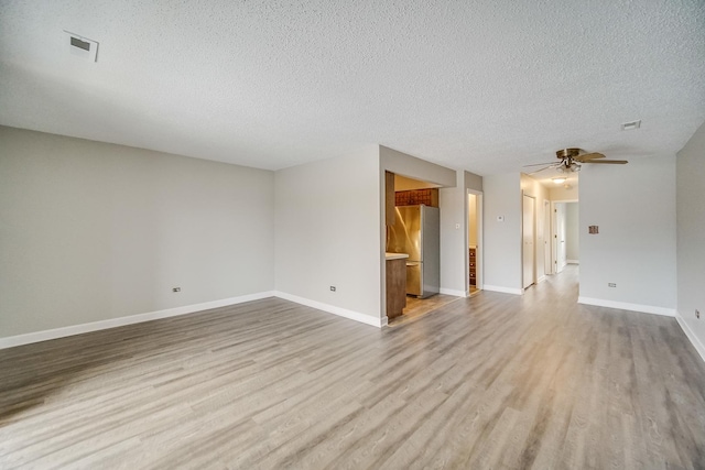 unfurnished room featuring light wood finished floors, baseboards, visible vents, a ceiling fan, and a textured ceiling