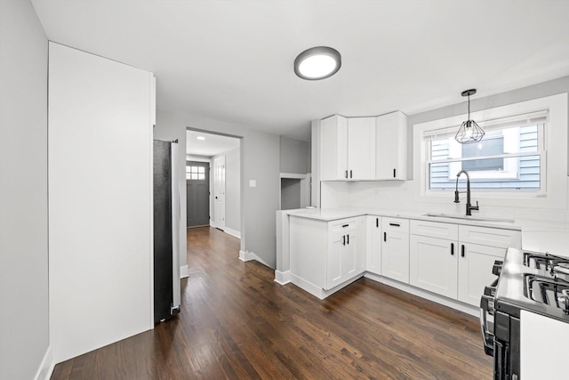 kitchen with light countertops, white cabinets, a sink, and black gas range