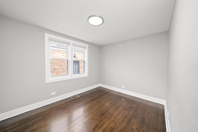 empty room featuring baseboards, visible vents, and dark wood-style flooring