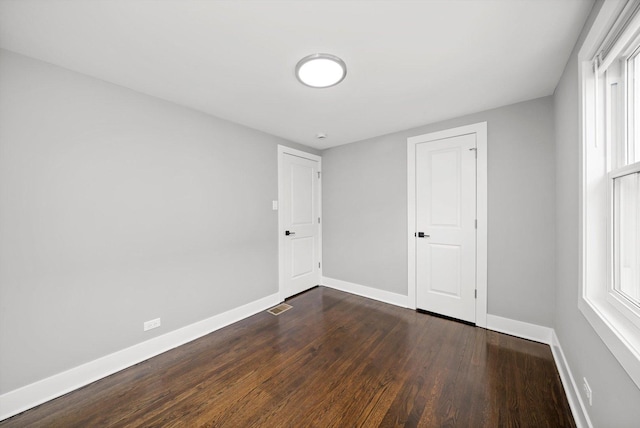 interior space featuring dark wood-type flooring, visible vents, and baseboards