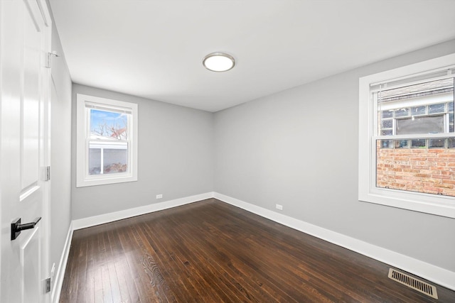 unfurnished room featuring baseboards, visible vents, and dark wood finished floors