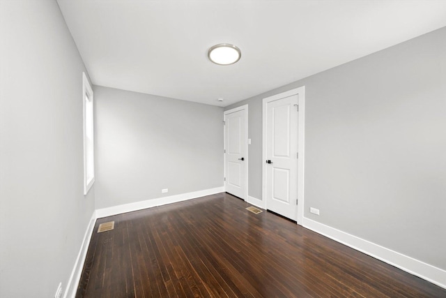 unfurnished bedroom featuring dark wood-style floors, visible vents, and baseboards