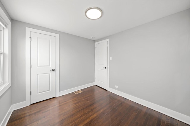 unfurnished bedroom featuring baseboards, visible vents, and dark wood finished floors