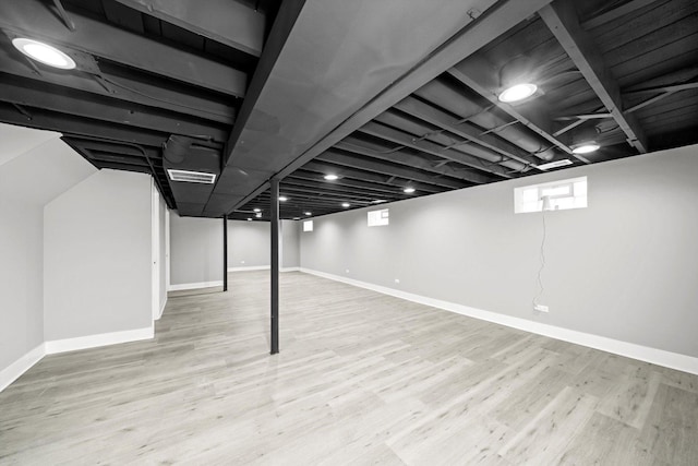 below grade area with visible vents, light wood-style flooring, and baseboards