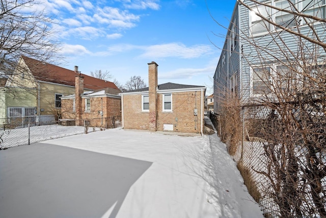 snow covered house with fence and brick siding