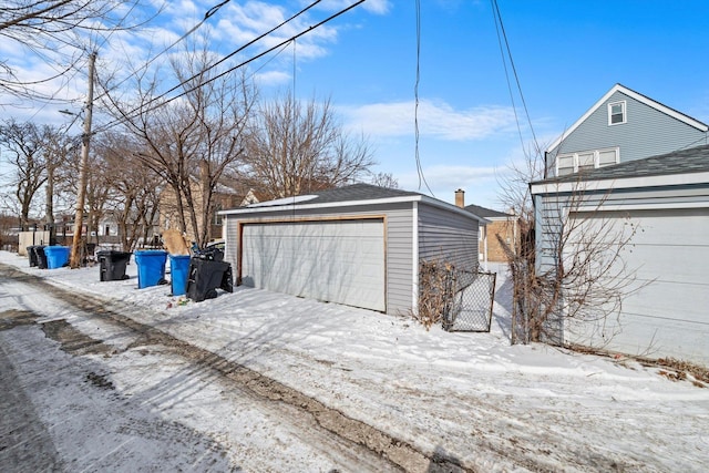 snow covered garage with a detached garage and fence