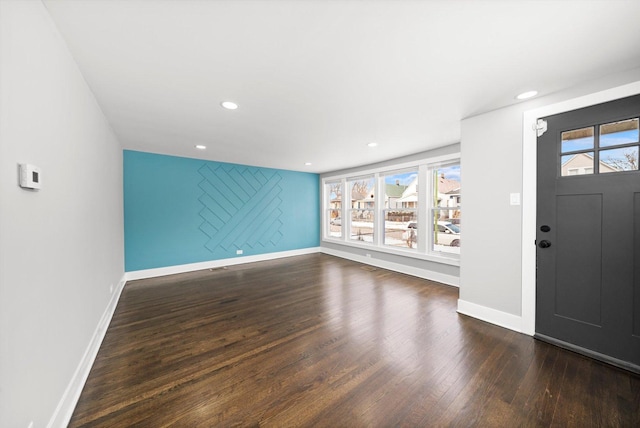 foyer featuring dark wood-style floors, recessed lighting, an accent wall, and baseboards