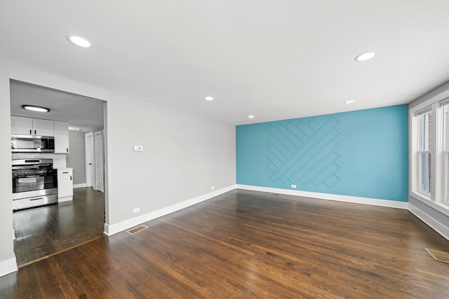 unfurnished living room featuring baseboards, dark wood finished floors, and recessed lighting