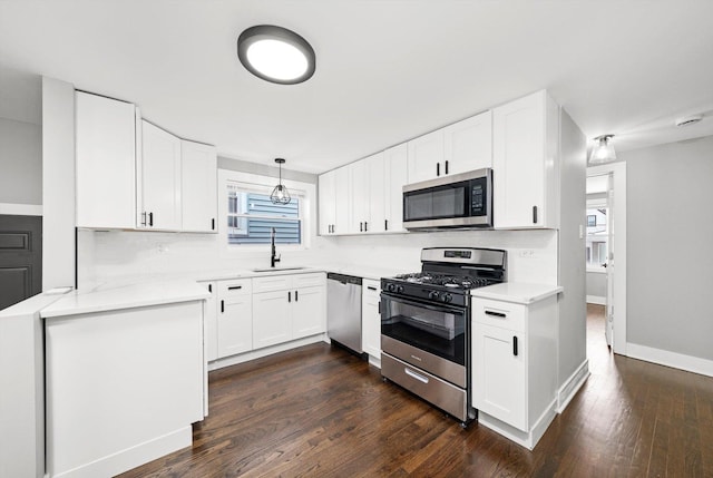 kitchen with white cabinetry, stainless steel appliances, light countertops, and pendant lighting