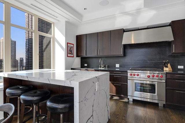 kitchen with a view of city, premium stove, a kitchen island, and exhaust hood