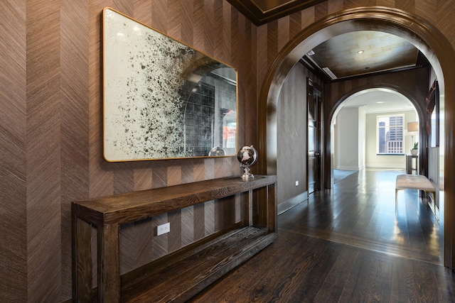 hall with baseboards, arched walkways, and wood finished floors