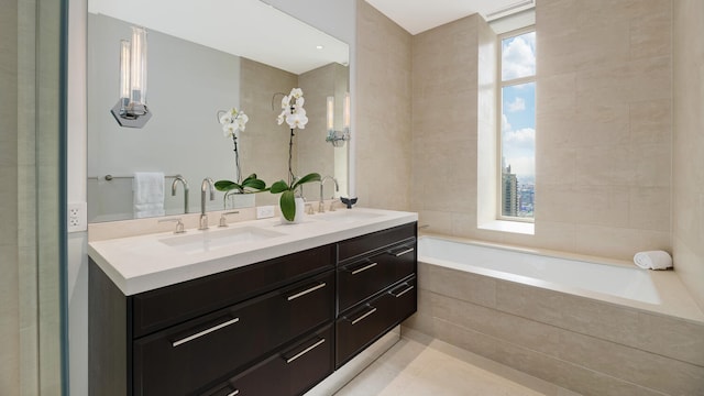 full bathroom with double vanity, a relaxing tiled tub, and a sink