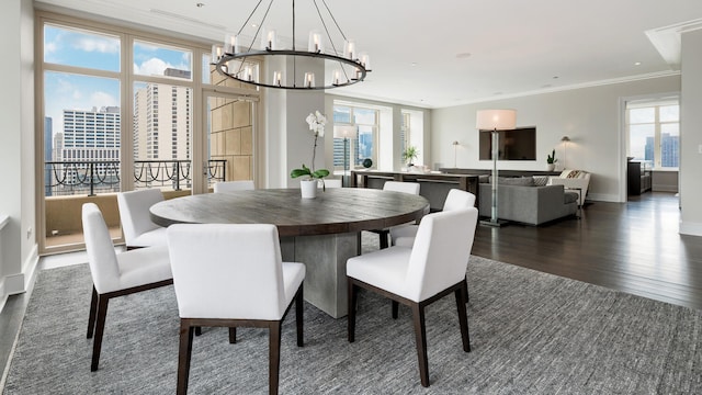 dining room featuring baseboards, ornamental molding, dark wood-type flooring, a city view, and a chandelier