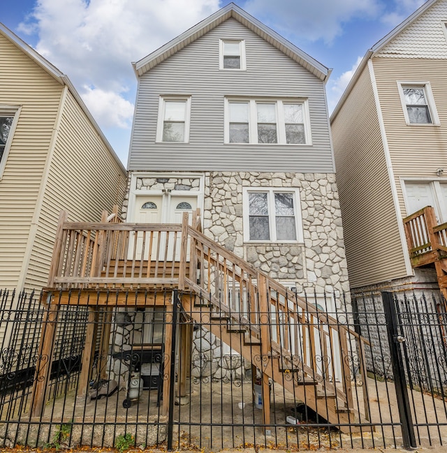 view of front of home with a fenced front yard, stone siding, stairway, and a gate