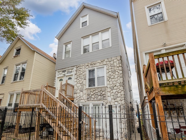 rear view of property featuring a fenced front yard and stone siding