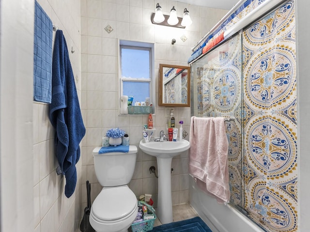 full bathroom with a sink, shower / bath combo with shower curtain, toilet, and tile walls